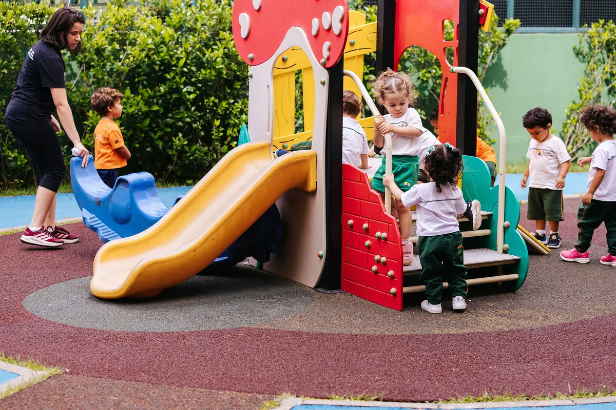 Crianças da Educação Infantil brincando no escorregador do parque